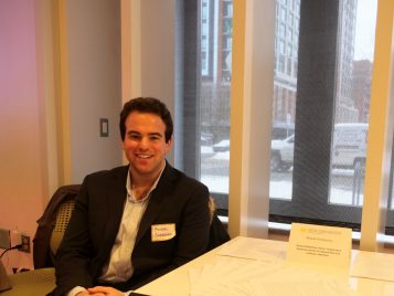 Michael Emmerman sitting by copies of his essay, "Temporal Rhythms Online: Imagining A Temporal Internet for Shared Rest and Collective Action."